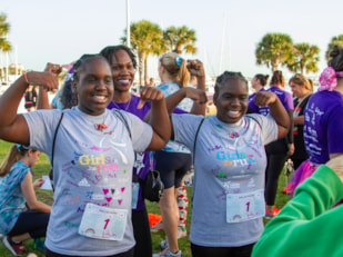 Girls on the Run participants gather with hands open to each other while they doing an activity